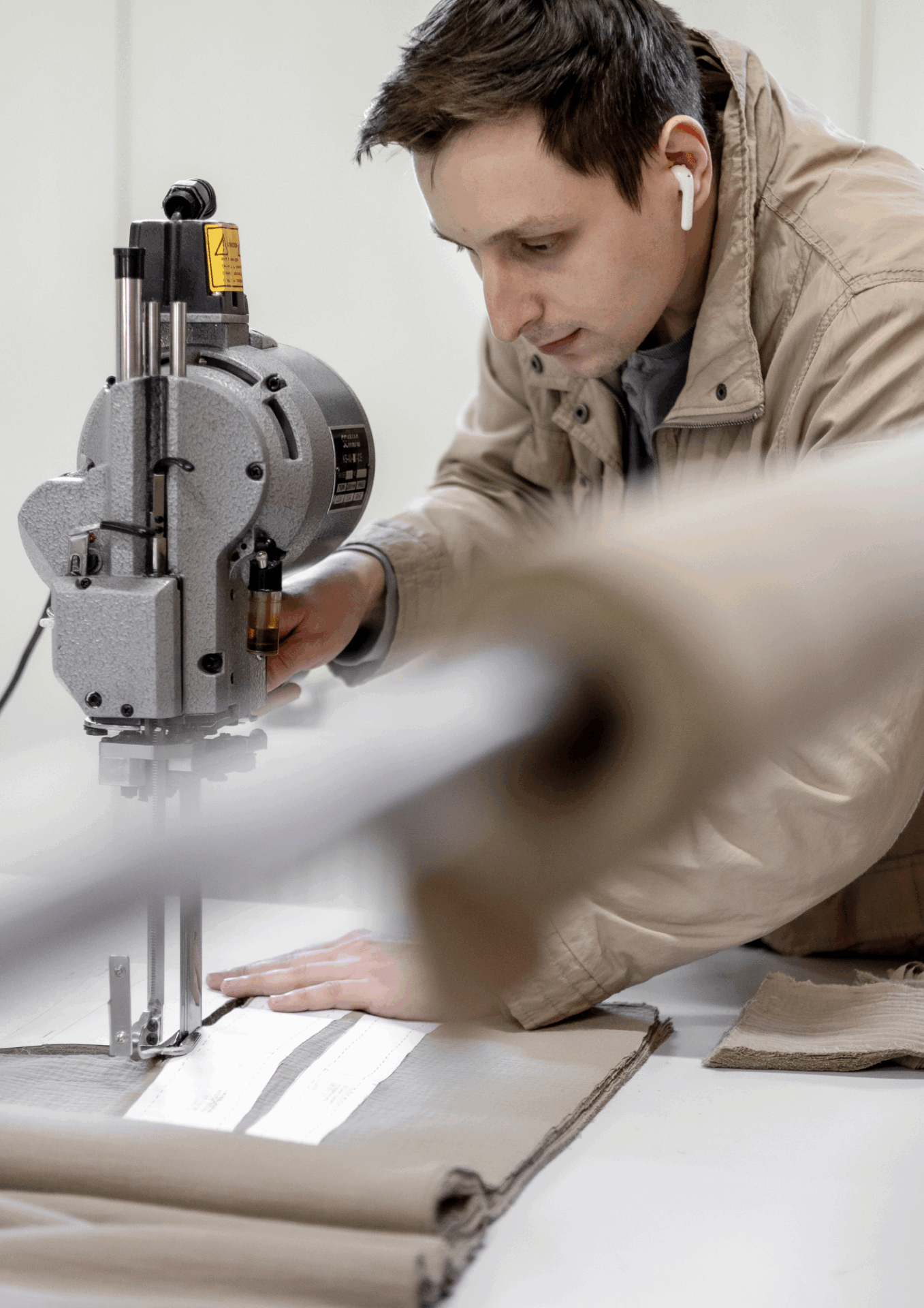 Zuschnitt von Stoff mit elektrischem Schneidemesser in der Schlei Schneiderei